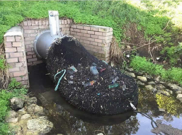 Filet à déchets fixé à une sortie de caniveau urbain dans une ville d'Amérique du Sud